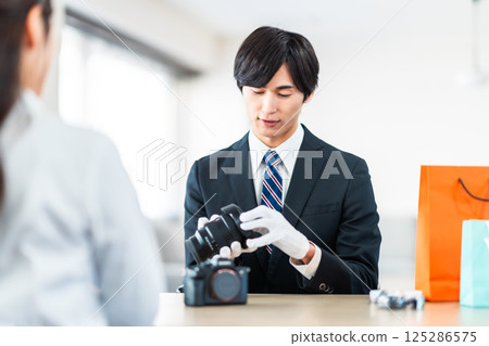 A specialist buyer assessing used goods and a housewife bringing in unwanted items to the store 125286575