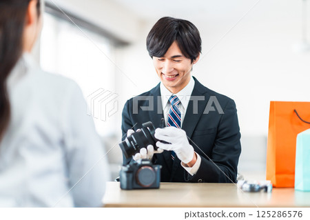 A specialist buyer assessing used goods and a housewife bringing in unwanted items to the store 125286576