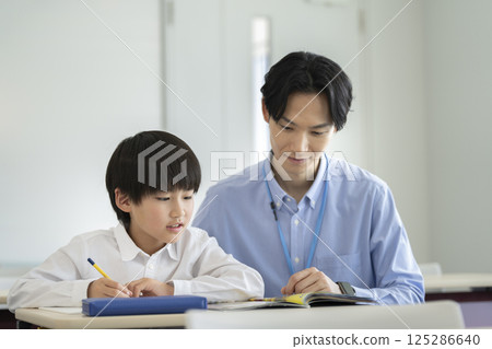 A fourth grade boy studying with his teacher A fourth grade boy studying with his teacher 125286640
