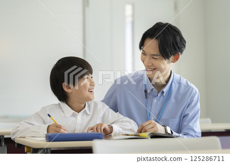 A fourth grade boy studying with his teacher A fourth grade boy studying with his teacher 125286711