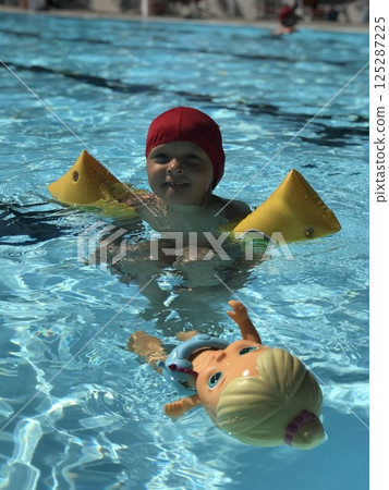 Child Enjoying Swimming Pool with Toy Doll Child Enjoying Swimming Pool with Toy Doll 125287225