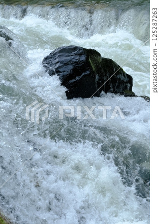 A close-up of the water flow of the Takano River swollen during the rainy season 125287263