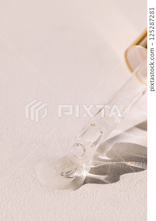 Close-up of a glass pipette with a drop of moisturizing serum with bubbles. Cosmetic products Close-up of a glass pipette with a drop of moisturizing serum with bubbles. Cosmetic products 125287281