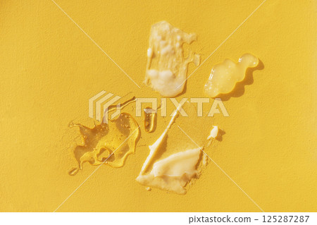 Different texture of gel and cream on a yellow background. Transparent and white serum with drops Different texture of gel and cream on a yellow background. Transparent and white serum with drops 125287287