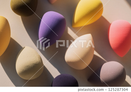 Colorful makeup sponges on a light background. A set of soft bright sponges in the form of a drop in the sunlight. 125287304