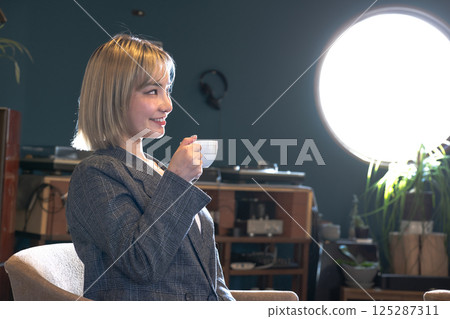 年輕女子在有圓形窗戶的咖啡店裡喝咖啡 年輕女子在有圓形窗戶的咖啡店裡喝咖啡 125287311