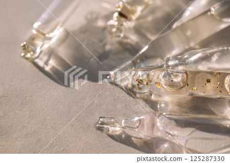 Close-up of glass pipettes with moisturizing serum with colloidal gold. Droppers with toning essence for facial skin with transparent drops on a white background. 125287330