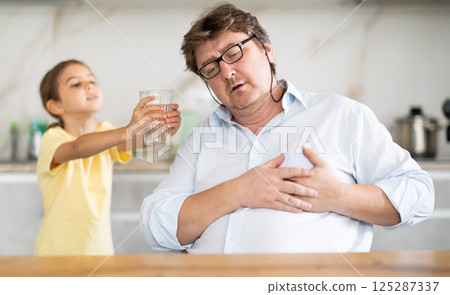 My father heart ached. Little daughter gives her father glass of water 125287337