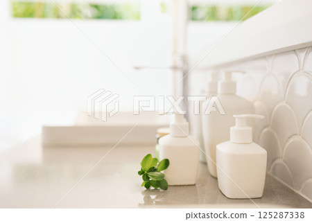 Close-up of ceramic jars with cream or soap on the marble countertop in the bathroom. Mockups of cosmetics at home. Layouts of bottles with dispensers. 125287338