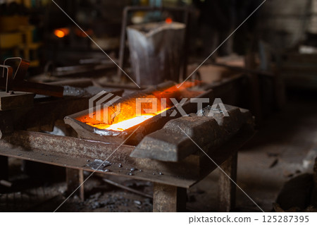 Mold with molten metal in the foundry workshop of metallurgical plant 125287395