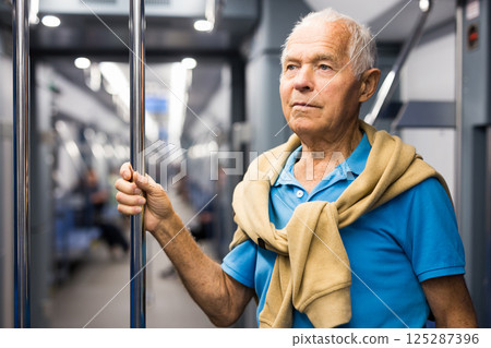 Old man standing in subway car 125287396