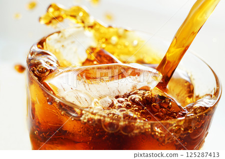 Iced coffee being poured vigorously into a glass with a splash 125287413