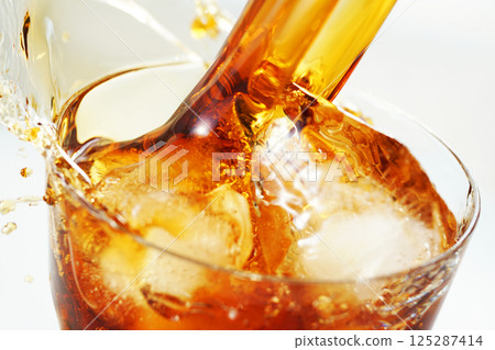 Iced coffee being poured vigorously into a glass with a splash Iced coffee being poured vigorously into a glass with a splash 125287414