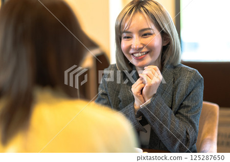 Two young women having a conversation in a coffee shop 125287650