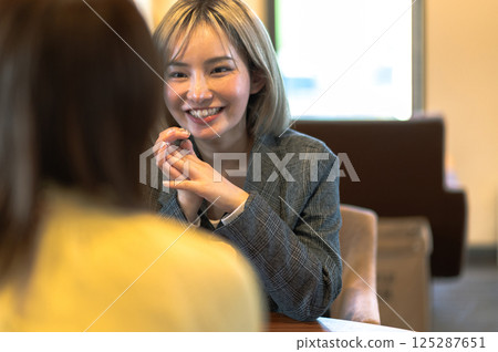 Two young women having a conversation in a coffee shop 125287651