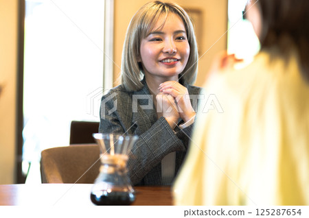 Two young women having a conversation in a coffee shop Two young women having a conversation in a coffee shop 125287654