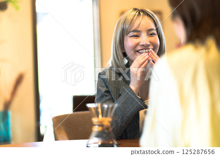 Two young women having a conversation in a coffee shop 125287656
