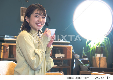 Young woman drinking coffee in a coffee shop with round windows 125288012