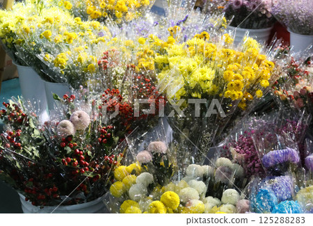 an array of vibrant floral arrangements being sold in the store with flower in plastic container including bundles of yellow, white blue and pink chrysanthemums in the night market an array of vibrant floral arrangements being sold in the store with flower in plastic container including bundles of yellow, white blue and pink chrysanthemums in the night market 125288283