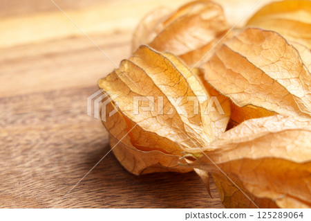 Physalis peruviana fruits in husk on wooden surface. Ground cherries close up.  125289064