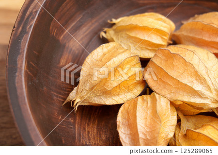 Cape Gooseberry (Physalis) fruits with husk in a wooden bowl. Top view. Macro shot.  125289065
