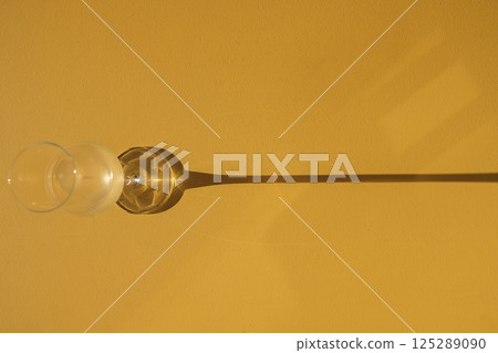 A close-up of glass with alcoholic beverage on a yellow background. Cup with sparkling wine. Top of view. Champagne goblet on a bright backdrop. A close-up of glass with alcoholic beverage on a yellow background. Cup with sparkling wine. Top of view. Champagne goblet on a bright backdrop. 125289090