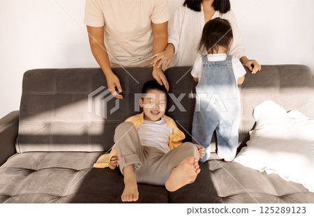 A Korean couple and their cute little kids on the sofa in the living room A Korean couple and their cute little kids on the sofa in the living room 125289123