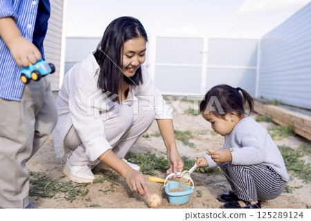 An Asian mom and her small children play in the sand in their daily clothes An Asian mom and her small children play in the sand in their daily clothes 125289124