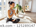 Asian woman has closed her eyes and is sitting in lotus position 125289147