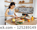 Young attractive Asian woman prepares delicious sandwich with fish and avocado 125289149