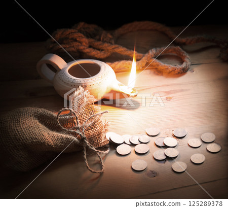 An oil lamp and silver coins 125289378