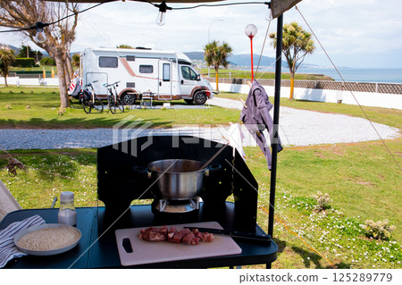 Coastal campsite cooking setup with camper van and scenic ocean view 125289779