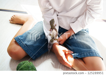 Boy interacts with leopard gecko in a cozy indoor setting during afternoon playtime Boy interacts with leopard gecko in a cozy indoor setting during afternoon playtime 125289951