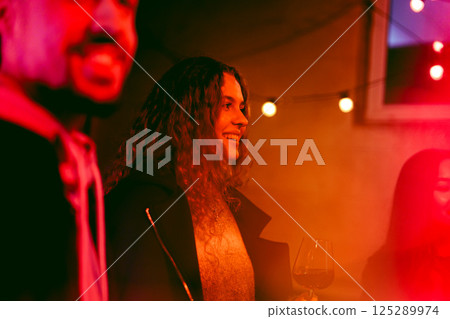 Friends celebrate at a lively indoor gathering with drinks and warm lights during a joyful evening 125289974