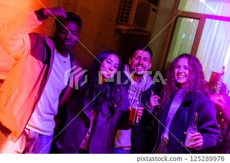 Friends enjoying a lively night out at a modern lounge with colorful lighting in the background 125289976