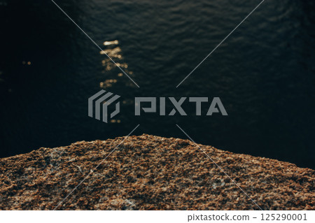 Rock podium. Seashore and stone parapet texture. Dark water in a sea, ocean aerial view selective focus. Dark key abstract seascape background. Rock podium. Seashore and stone parapet texture. Dark water in a sea, ocean aerial view selective focus. Dark key abstract seascape background. 125290001