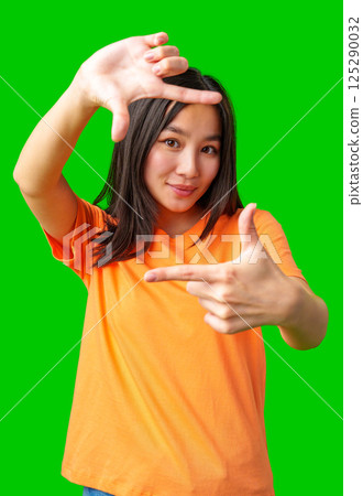 Young woman making hand gestures as if framing a scene against a bright green background Young woman making hand gestures as if framing a scene against a bright green background 125290032