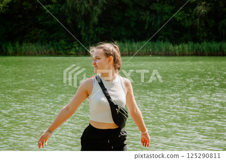 Young woman enjoying nature by a lake in summer. Weekend concept near the forest and lake Young woman enjoying nature by a lake in summer. Weekend concept near the forest and lake 125290811