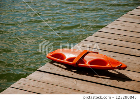 Lifeguard rescue float on wooden dock by lake water surface in summer. Weekend concept near the forest and lake 125290843