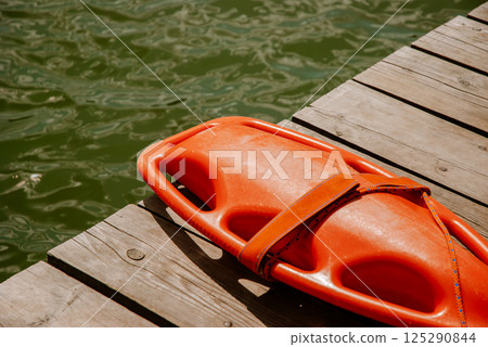Lifeguard rescue float on wooden dock by calm lake water. Weekend concept near the forest and lake 125290844