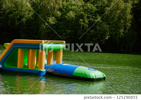 Inflatable water park obstacle course on a lake amidst lush greenery. Weekend concept near the forest and lake Inflatable water park obstacle course on a lake amidst lush greenery. Weekend concept near the forest and lake 125290855