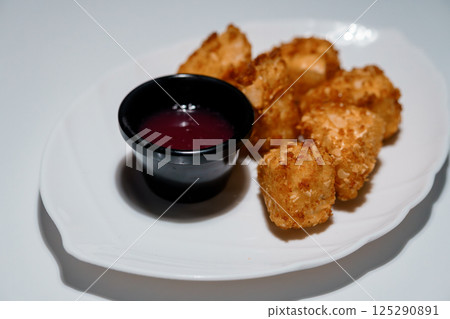 Crispy tater tots served with a vibrant purple dipping sauce on a white plate, studio shot showcasing fast food snack presentation Crispy tater tots served with a vibrant purple dipping sauce on a white plate, studio shot showcasing fast food snack presentation 125290891