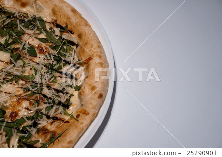 Delicious pizza with mozzarella, arugula, balsamic glaze served on a white plate, close-up shot, food photography 125290901