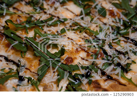 Close-up of gourmet pizza with mozzarella, arugula, balsamic glaze and parmesan cheese on a rustic crust, appetizing food photography Close-up of gourmet pizza with mozzarella, arugula, balsamic glaze and parmesan cheese on a rustic crust, appetizing food photography 125290903