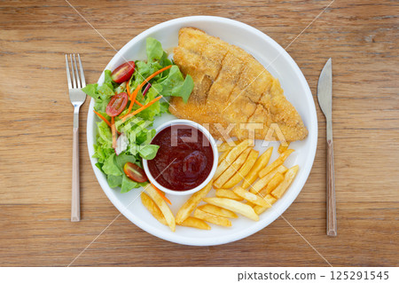 Fish steak with vegetable salad and french fries on a plate, top view Fish steak with vegetable salad and french fries on a plate, top view 125291545