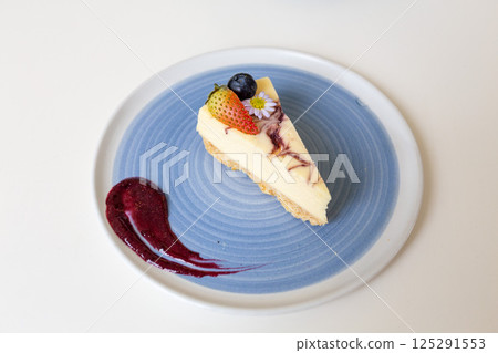 Close-up of a slice of cheesecake on a plate on a table in a cafe. Close-up of a slice of cheesecake on a plate on a table in a cafe. 125291553