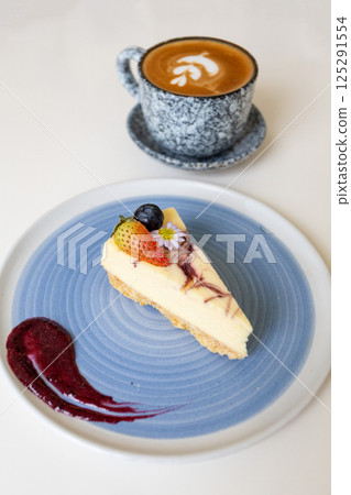 Close-up of a slice of cheesecake on a plate on a table in a cafe. Close-up of a slice of cheesecake on a plate on a table in a cafe. 125291554