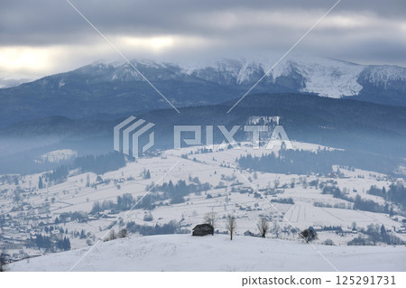 Winter landscape with small village houses between snow covered forest in cold mountains Winter landscape with small village houses between snow covered forest in cold mountains 125291731