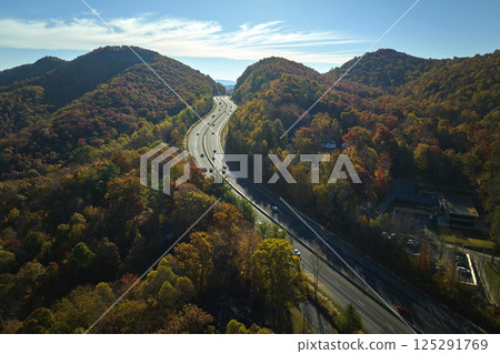 View from above of I-40 freeway route in North Carolina leading to Asheville thru Appalachian mountains with yellow fall woods and fast moving trucks and cars. Interstate transportation concept 125291769