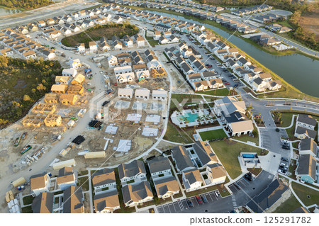 Unfinished frames of inexpensive homes with wooden roof beams under construction. Development of residential housing in US suburbs. Real estate market in the USA 125291782